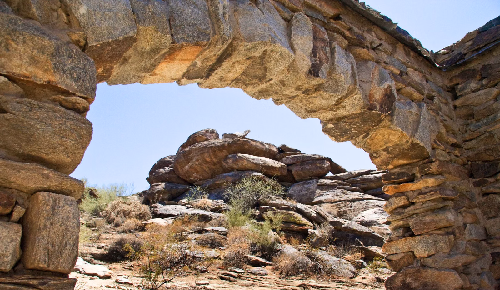 Arched stone wall of the Dobbins Lookout ramada framing a desert rock formation